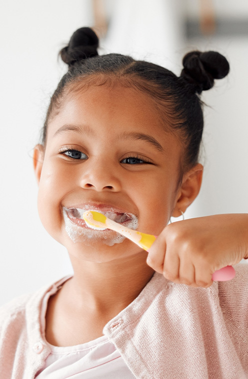 Young girl smiling while brushing her teeth