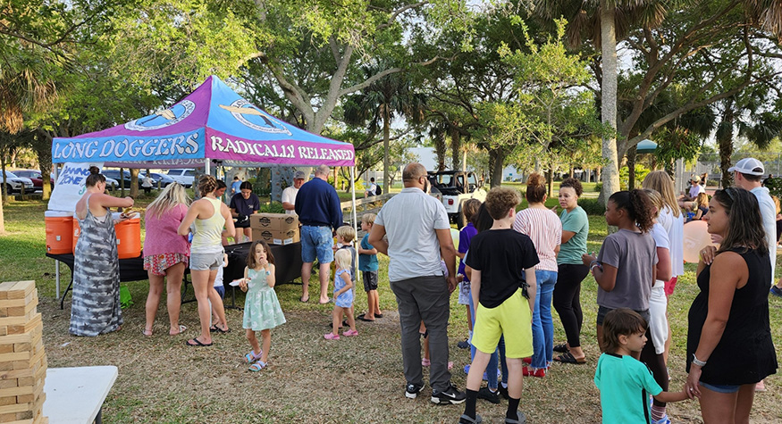 Several families standing in line for table at outdoor event