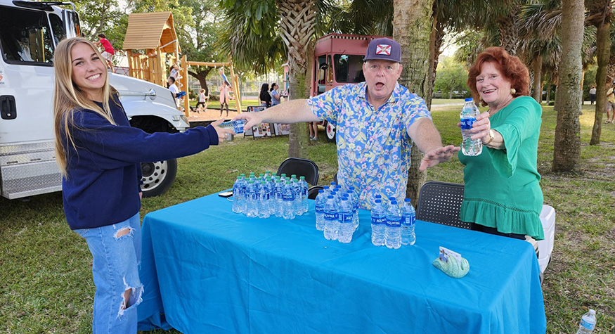 Volunteers handing out water bottles at table at outdoor event