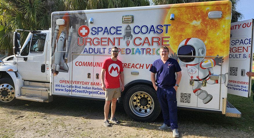 Doctor Brandon Millard smiling next to an urgent care ambulance