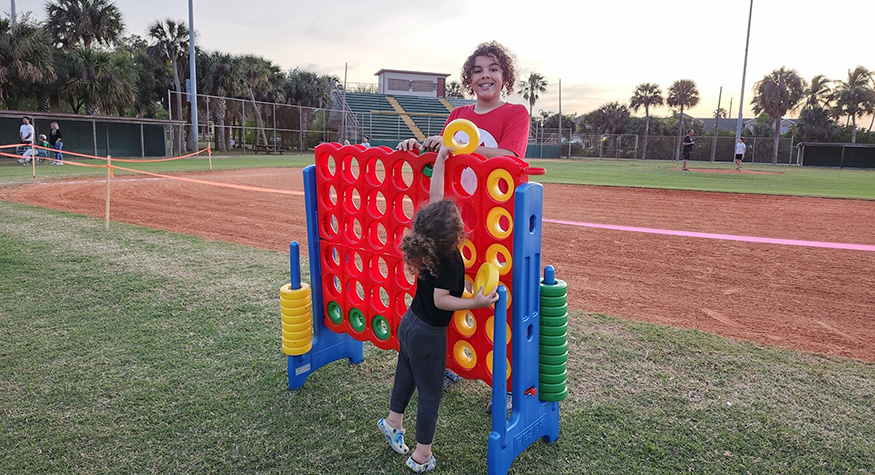 Two kids playing a ring stacking game outdoors