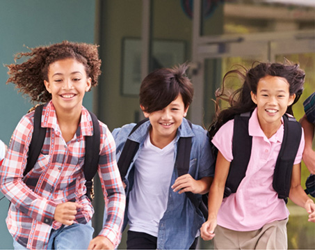 Three kids with backpacks running