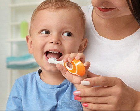 Mother helping her baby brush their teeth