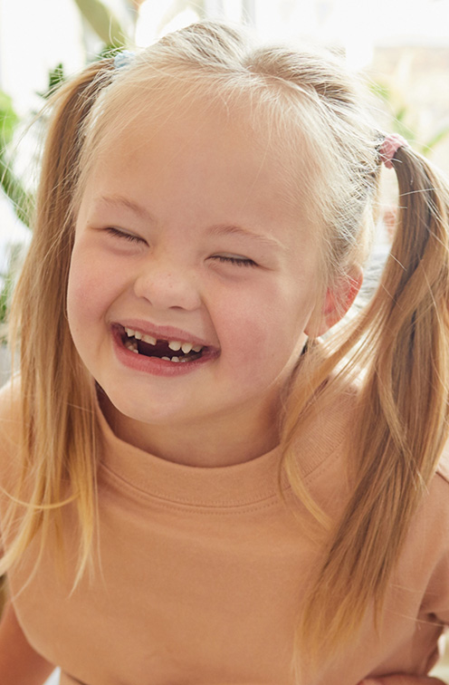 Blonde girl with pigtails grinning after seeing pediatric special needs dentist in Satellite Beach