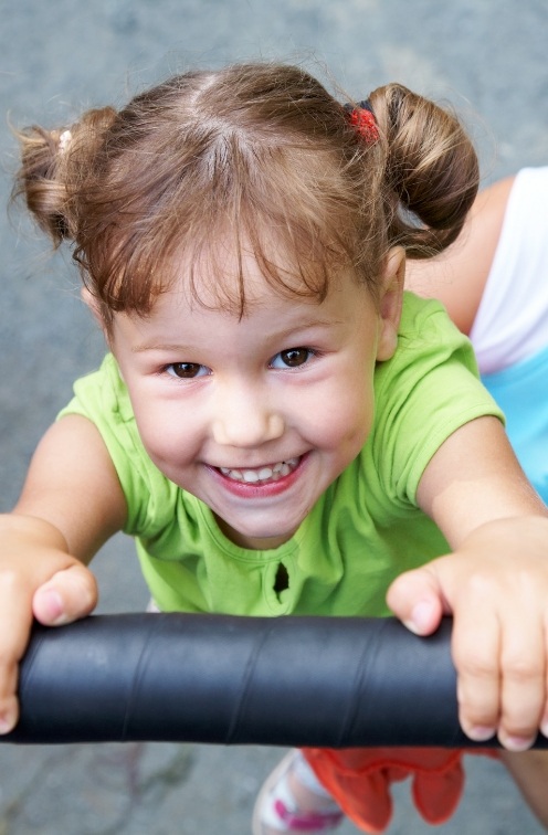 Young girl with pigtails smiling after seeing dentist for toddlers in Satellite Beach