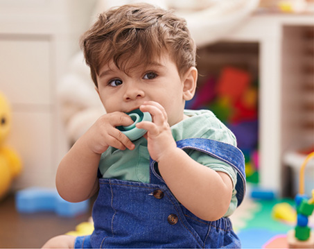 Toddler boy chewing on a teething ring