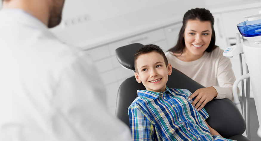 Young boy in dental chair smiling at his pediatric dentist