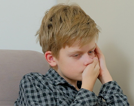 Young boy holding his face in pain