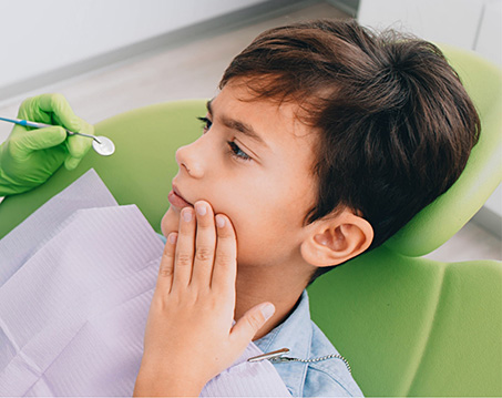 Young boy wincing in pain in dental chair