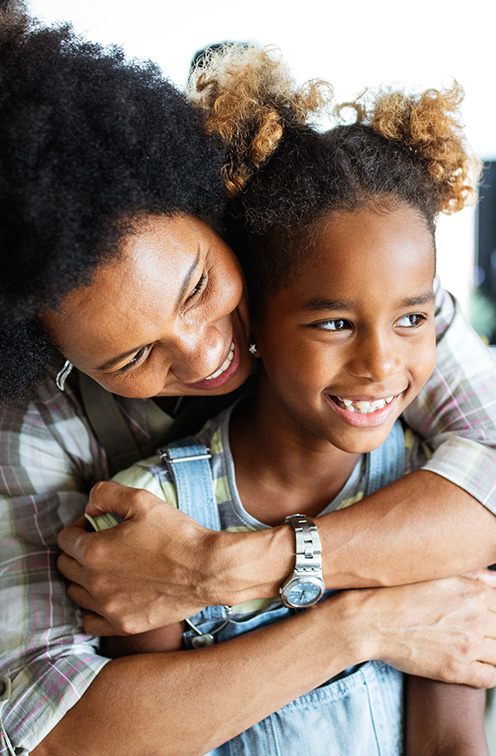 Smiling mother hugging her daughter from behind