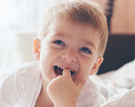 Smiling young boy touching his teeth