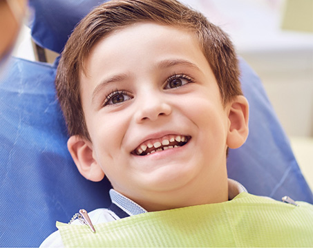 Boy in dental chair smiling at his dentist