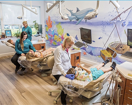 Two children receiving treatment from pediatric dentists