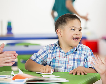 Young boy smiling while sitting at desk with papers